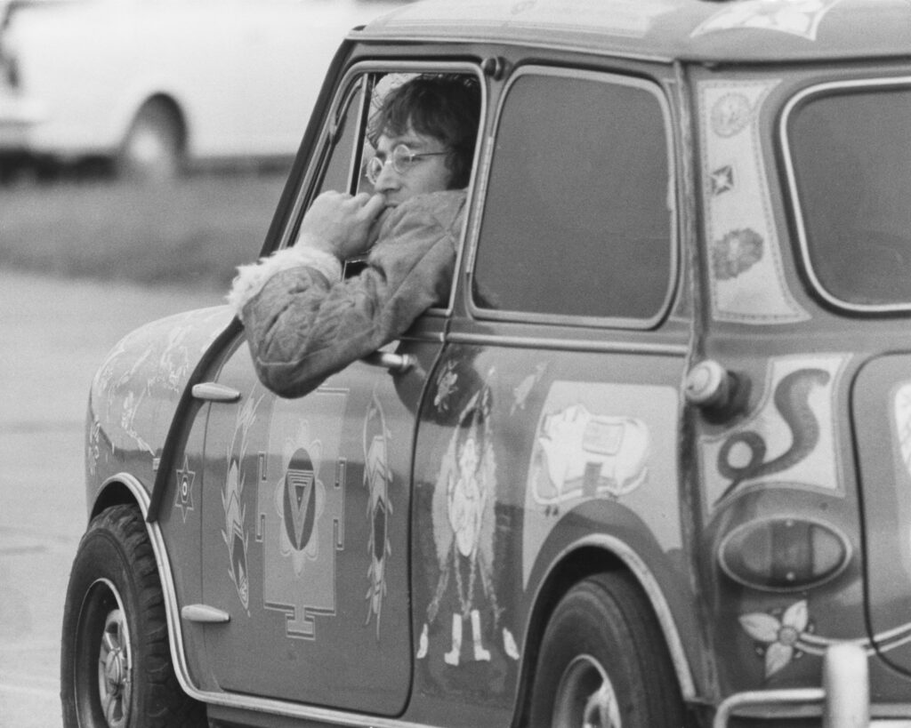 John Lennon met de Mini van George Harrison.