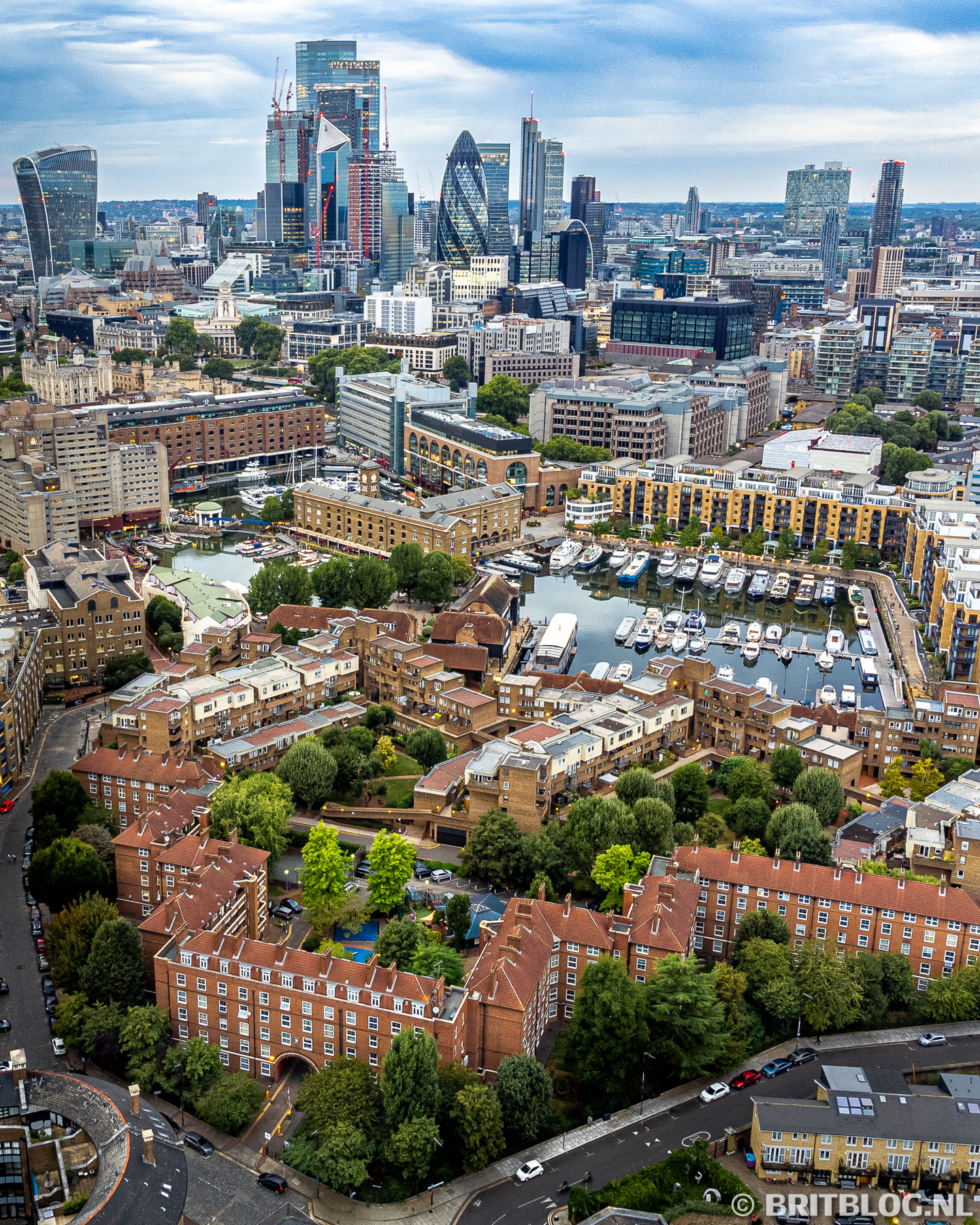 Luchtfoto van St. Katharine Docks met uitzicht op de skyline van de City of London, inclusief iconische gebouwen als The Gherkin, The Scalpel en de Walkie Talkie.