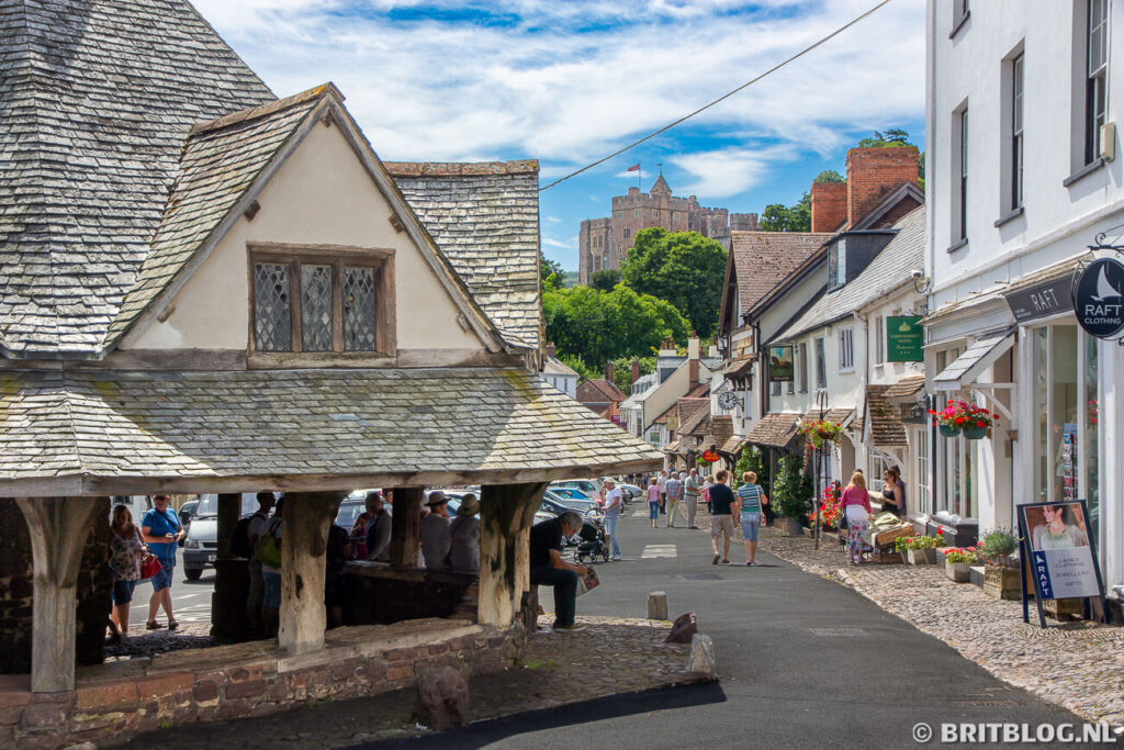 Yarn Market, winkels en op de achtergrond Dunster Castle op een zonnige dag in Somerset, Engeland.
