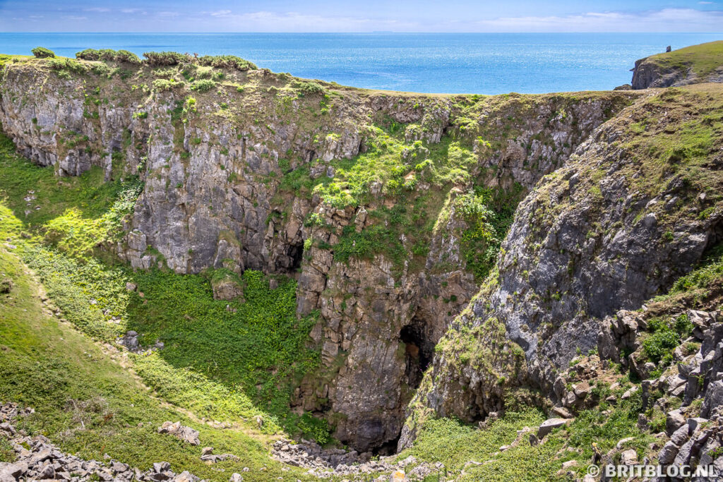 Een kuil met daarachter de zee langs Pembrokeshire Coast Path