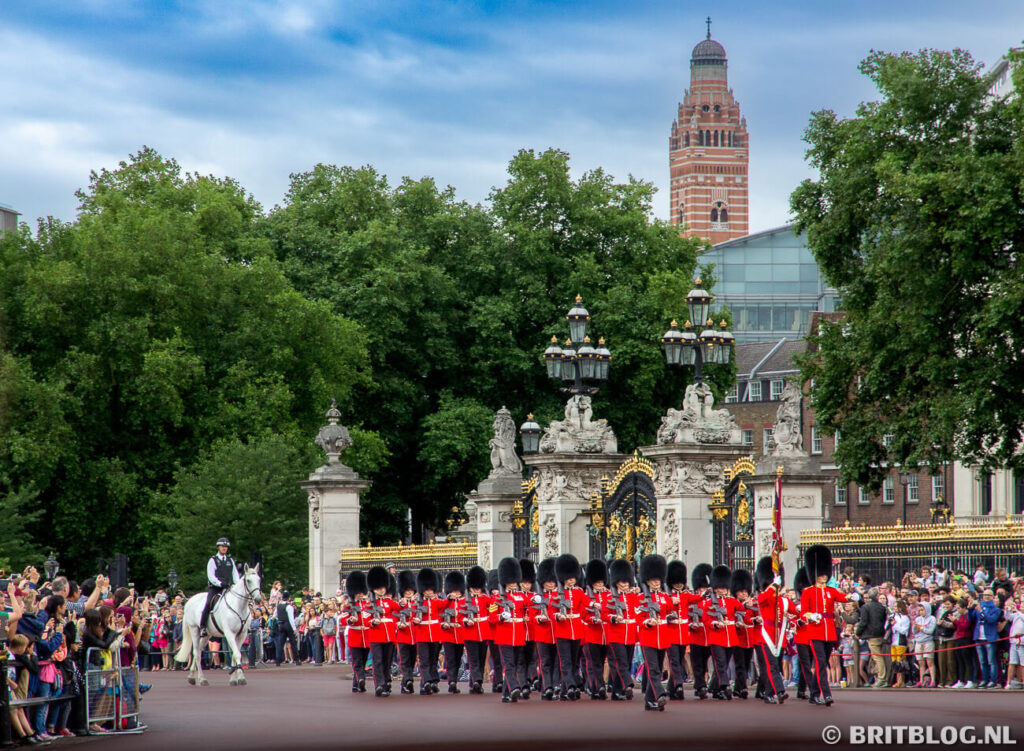 Wachters in rode tunieken en berenmutsen marcheren voor Buckingham Palace tijdens de Changing of the Guard in Londen.