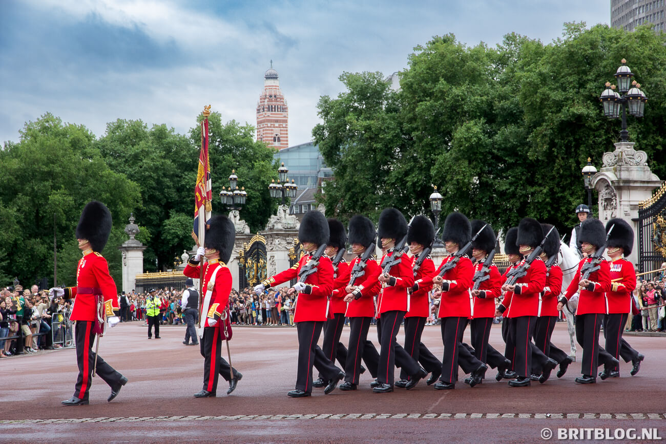 Wisseling van de wacht bij Buckingham Palace in Londen met wachters in rode uniformen en berenmutsen.
