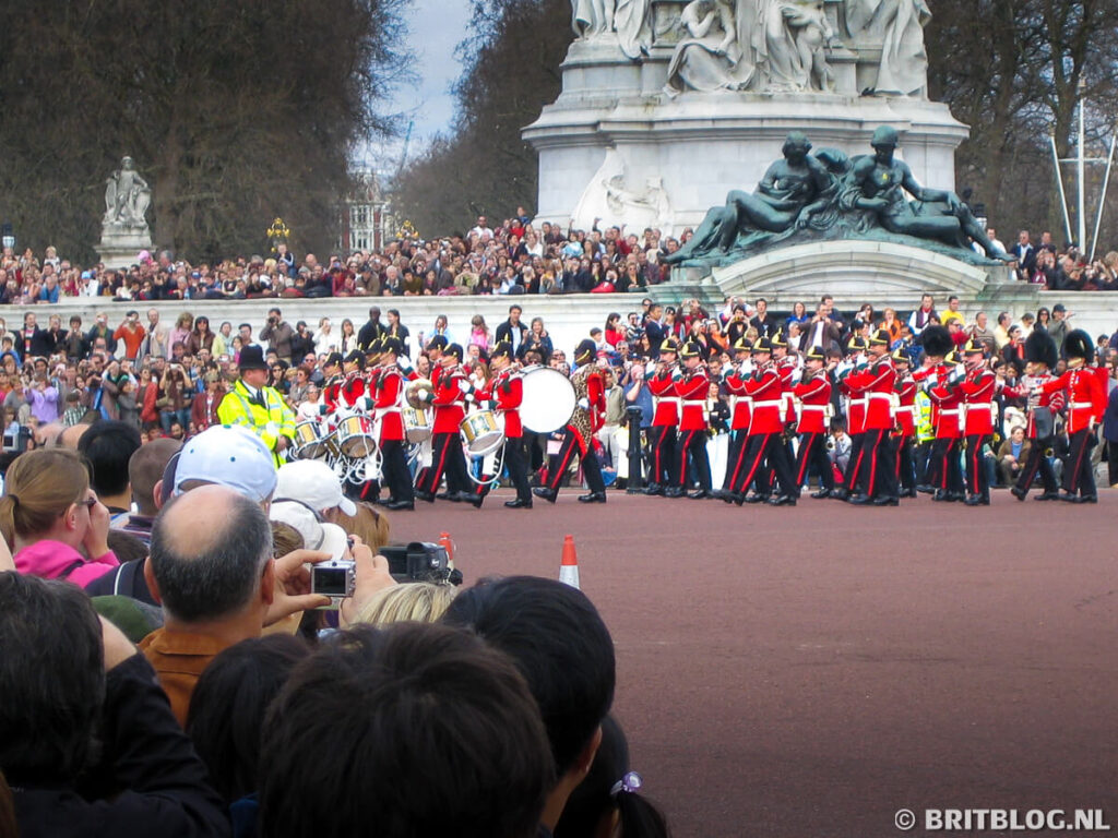 Militaire band en wachters in rode uniformen voeren de Changing of the Guard-ceremonie uit bij het Victoria Memorial voor Buckingham Palace.