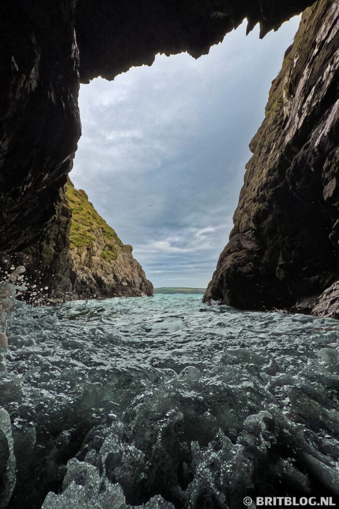 Zicht vanuit een zeegrot bij Abercastle, Pembrokeshire, met uitzicht op de kustlijn en het blauwe water.
