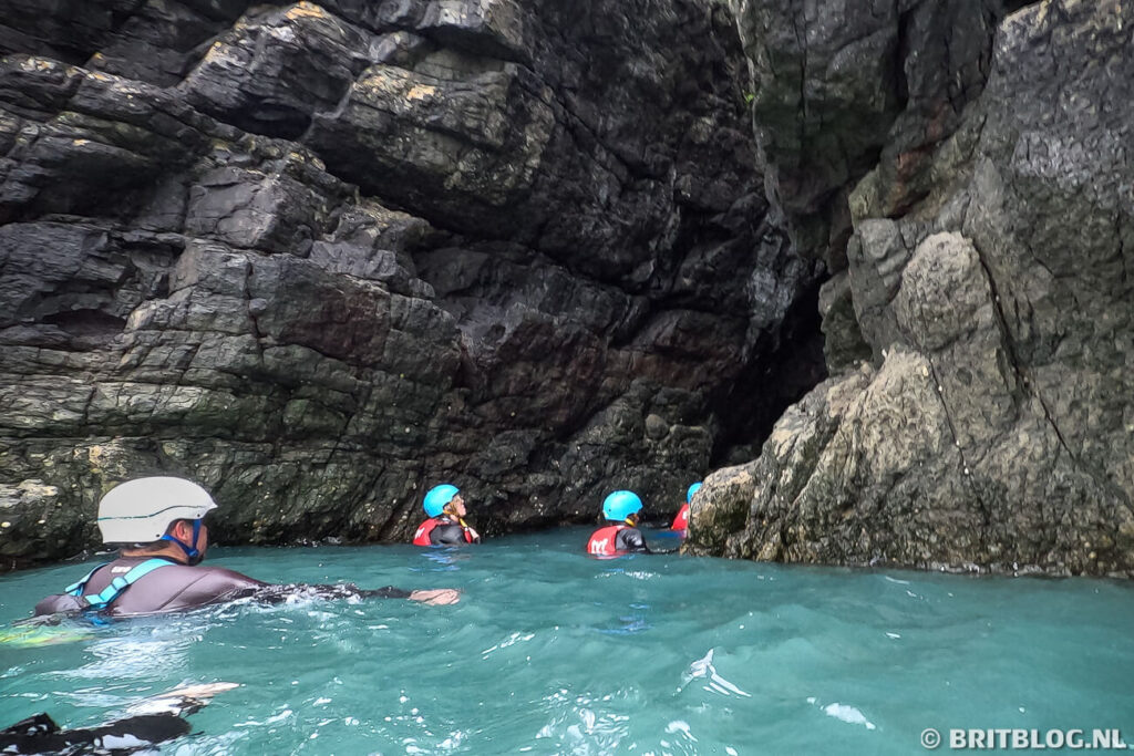 Coasteering in Pembrokeshire, deelnemers zwemmen tussen de kliffen richting de grot van Ynys-y-Castell.