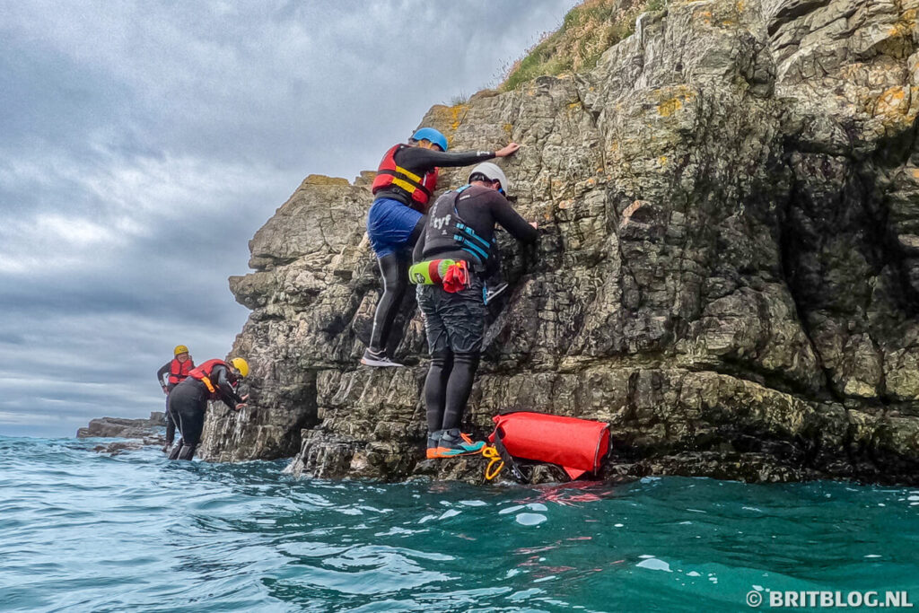 Tijdens coasteering klimmen we langs rotsen bij Abercastle, Pembrokeshire.