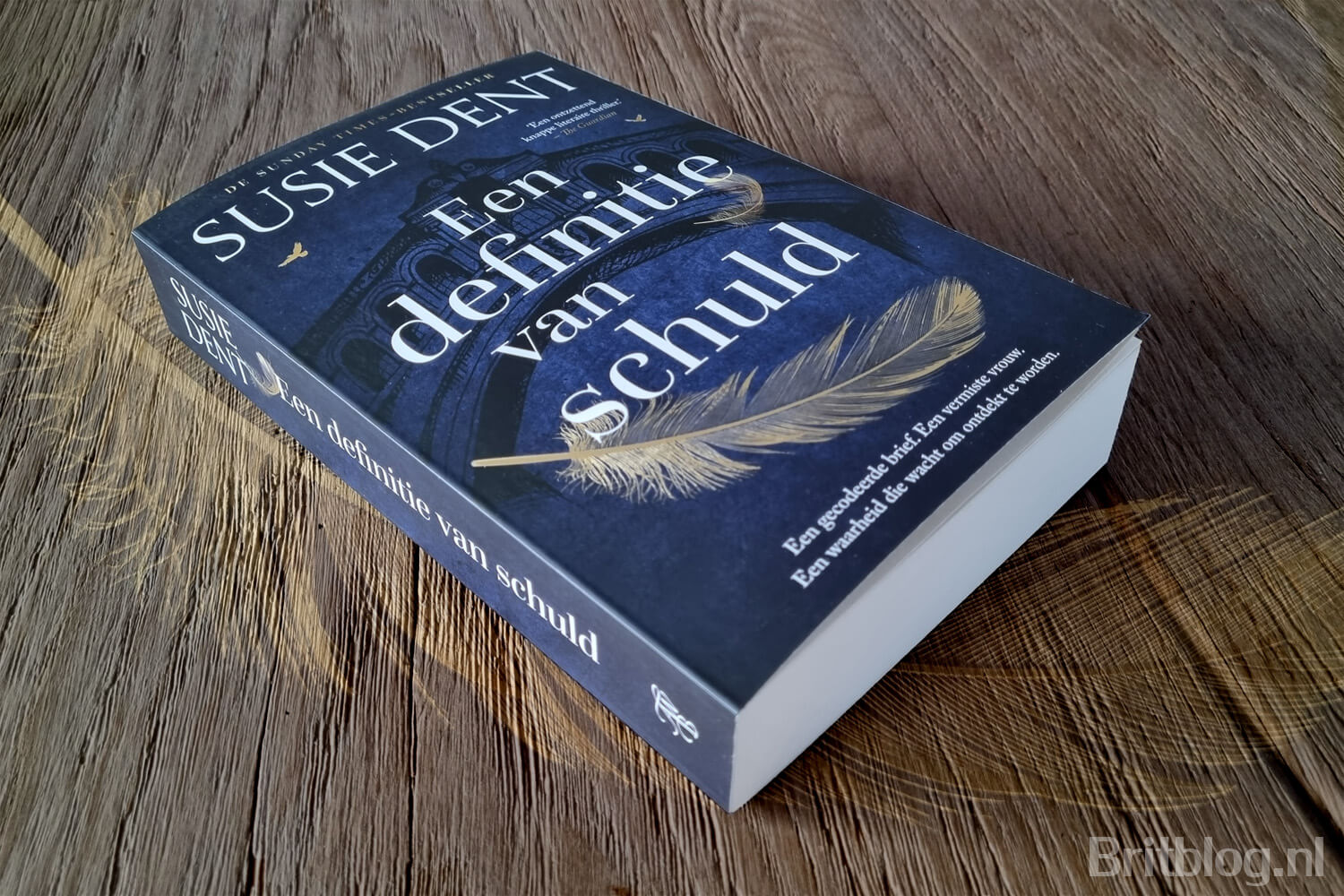 Het boek Een definitie van schuld van Susie Dent op een houten tafel.